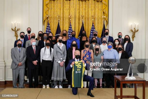 President Joe Biden holds a jersey as he poses for a photo with the 2020 WNBA champions Seattle Storm in the East Room of the White House on August...