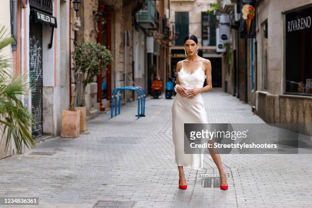 Model and artist Zoe Helali wearing a white shadow pearl Elisabeth slip silk dress with shoulder straps, lace detail and a high one side slit by...