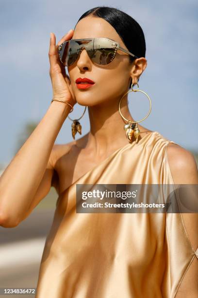 Model and artist Zoe Helali wearing a gold Beatrice silk dress with open one shoulder, loose silhouette and asymmetric hem by Sasha La Mer,...