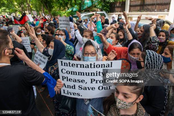 Afghan refugee women raise hands, hold placards and chant slogans during a protest in front of UNHCR office at Vasant Vihar, New Delhi. Hundreds of...