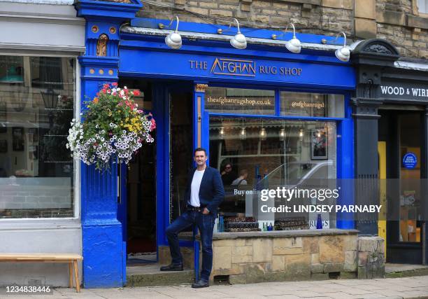 The Afghan Rug Shop owner James Wilthew poses for a photograph outside his shop Hebden Bridge, northern England, on August 20, 2021. - Overseas...