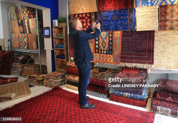 The Afghan Rug Shop owner James Wilthew photographs new arrivals on display to upload to the shop's social media accounts at his shop in Hebden...