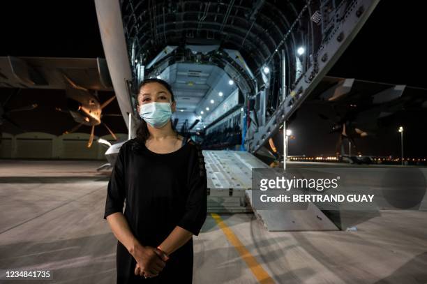 Woman poses in front of a A400M military transport aircraft after being evacuated from Kabul as part of the operation "Apagan" at the French military...
