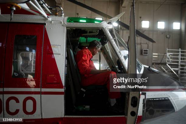 An on-board firefighter engineer inspecting the AB412 helicopter before a flight in Lamezia Terme , Italy, on August 23, 2021. The flight department...