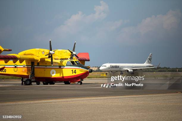 A Condor Airline Airbus A321 passes behind a Canadair firefighting plane, in Lamezia Terme , Italy, on August 23, 2021. The flight department of the...