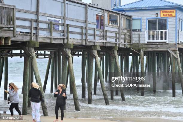 Group of women face heavy wind as they head for the Old Orchard Beach Pier during heavy winds from Hurricane Henri.