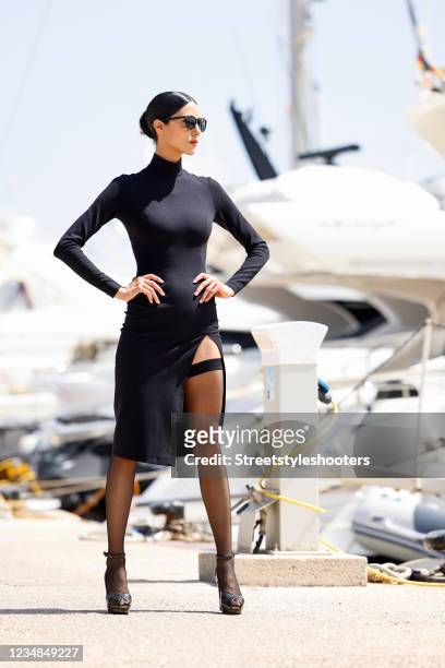 Model and artist Zoe Helali wearing a black midi length longsleeve turtleneck dress with thigh high slit by Wolford, black thigh high stay-up...