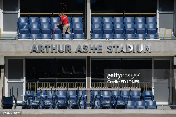 Worker sweeps a seating area at the Arthur Ashe stadium ahead of the 2021 US Open Tennis tournament at the Billie Jean King Natinal Tennis Center in...