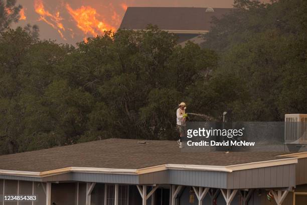 Man waters a rooftop as the French Fire approaches on August 24, 2021 in Wofford Heights, California. The 16,000-acre French Fire began August 18 and...