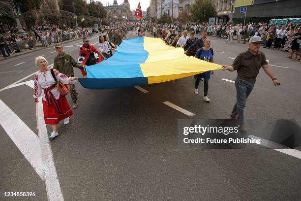 People carry a long Ukrainian flag during the March of Defenders of Ukraine 2021 held as part of the 30th Independence Day celebration, Kyiv, capital...