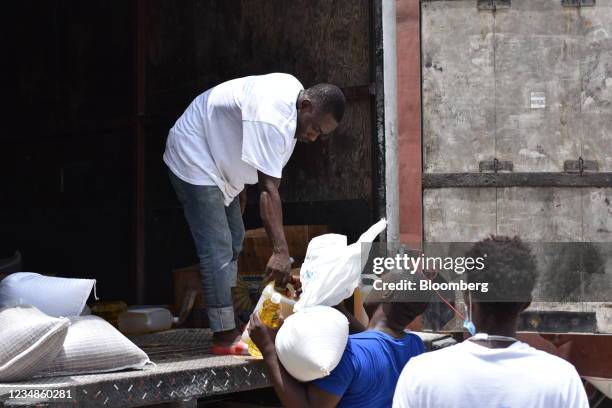 Worker hands out bags of rice and cooking oil to residents at a World Food Programme distribution site in Port-Salut, Haiti, on Tuesday, Aug. 24,...