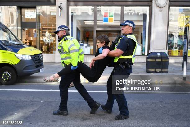 Climate activist from the Extinction Rebellion group is escroted away by police officers from a demonstration blocking the road in the middle of...