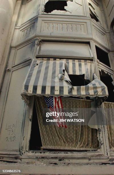 This US Navy image shows a flag blowing in the wind, contrasted by the soot covered building it rests upon 13 September 2001, in New York City. The...