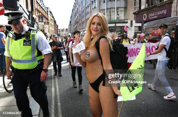 Topless protester seen with 'save a couple' of XR stickers marching to Oxford Circus, during the Impossible Rebellion Led by Female, Intersex,...