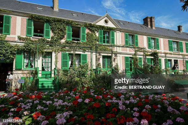 Visitors pose for a picture in front of French impressionist painter Claude Monet's house in Giverny, Northwestern France on August 25, 2021....