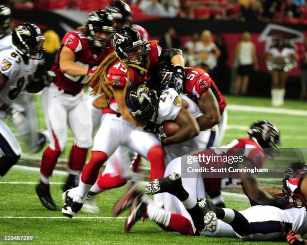 Damien Berry of the Baltimore Ravens carries the ball against Bear Woods of the Atlanta Falcons during a preseason game at the Georgia Dome on...