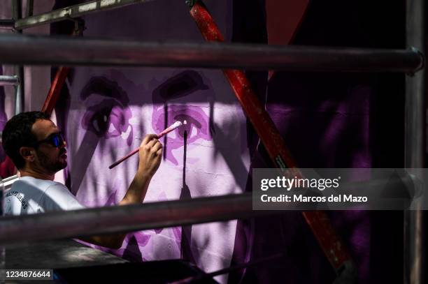 Member of UNLOGIC artistic group repainting a feminist mural that appeared vandalized during the past International Women's Day. The mural represents...