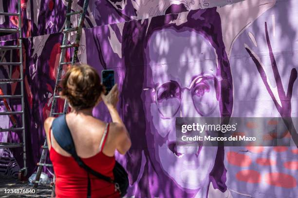 Woman takes pictures to a feminist mural that is being repainted by members of UNLOGIC artistic group. The mural appeared vandalized during the past...