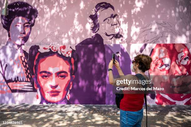 Woman takes pictures to a feminist mural that is being repainted by members of UNLOGIC artistic group. The mural appeared vandalized during the past...