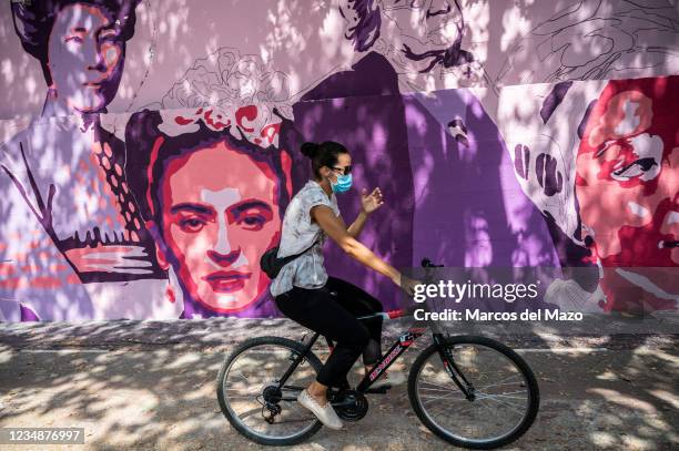 Woman riding a bike passing by a feminist mural that is being repainted by members of UNLOGIC artistic group. The mural appeared vandalized during...