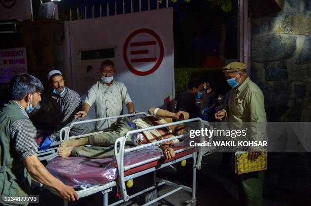 Graphic content / Medical and hospital staff bring an injured man on a stretcher for treatment after two powerful explosions, which killed at least...