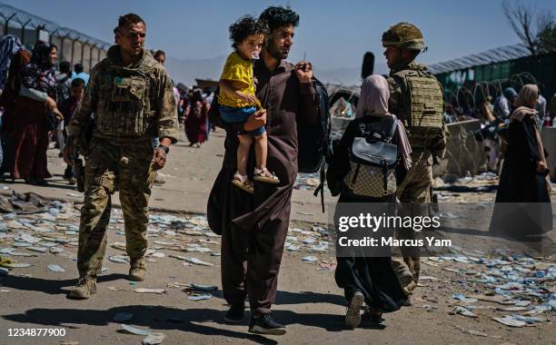 Afghan refugees make their way towards an intake near Abbey Gate, as British and American security forces maintain order amongst the Afghan evacuees...