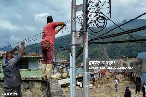 Residents try to fix wires of electrical power in an area where several homes were destroyed by a mudslide caused by heavy rains in Valle del...