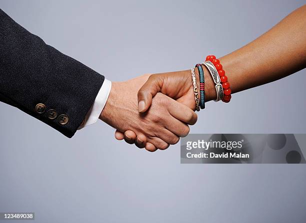 caucasian man shaking hands with an african woman - handshake closeup stock pictures, royalty-free photos & images