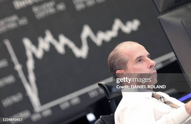 Trader works in front of a board displaying Germany's share index DAX at the stock exchange in Frankfurt am Main, western Germany, on August 27,...