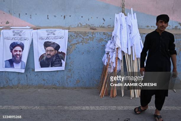 Vendor selling Taliban flags stands next to posters of Taliban leaders Mullah Abdul Ghani Baradar and Amir Khan Muttaqi as he waits for customers...