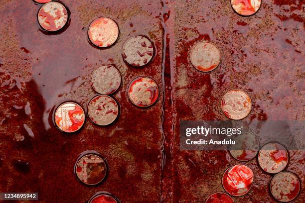 Coins thrown by members of climate change activist movement Extinction Rebellion lie covered in red liquid depicting blood, spread outside the London...