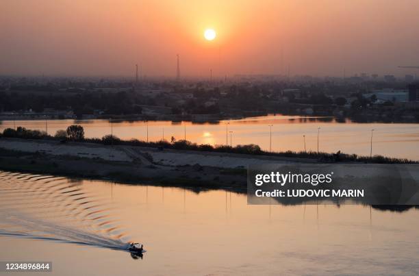 The sun sets behind the Tigris river in Iraq's capital Baghdad on August 27, 2021 ahead of a regional summit in the city. - After decades of...