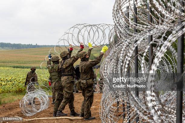 Polish Army Soldiers build a fence with concertina wire at the Belarusian border in order to stop immigrants from entering the country in Krynki,...