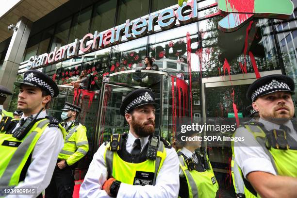 Police officers cordon off Standard Chartered bank as rebels daub the exterior with paint as part of the Impossible Rebellion, during the March. They...