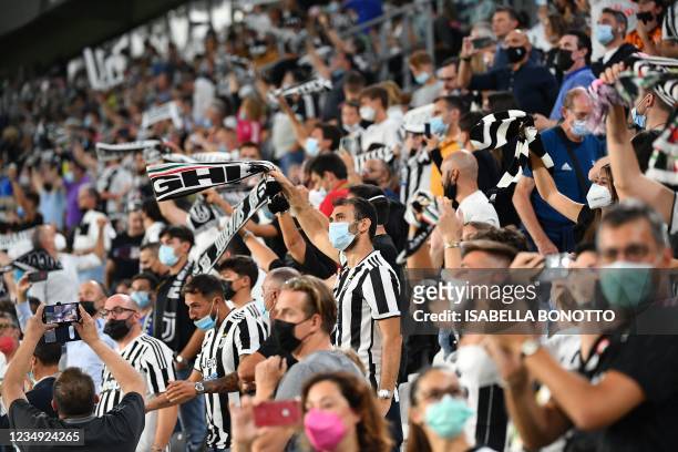 Juventus fans, wearing a face mask, cheer on their team during the Italian Serie A football match Juventus vs Empoli at Allianz Stadium in Turin, on...