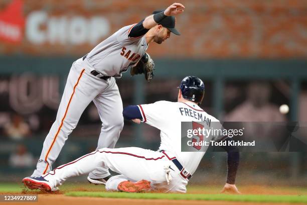 Tommy La Stella of the San Francisco Giants fails to catch the throw to second as Freddie Freeman of the Atlanta Braves slides in and proceeds to...