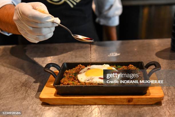 In this picture taken on July 16, 2021 a chef garnishes an egg over Keema - mince lamb meat with Kikkoman Soy Sauce at the Ishaara restaurant in...