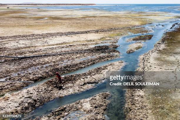 This picture taken on July 27, 2021 shows an aerial view of a man walking past a water pump drawing water from the Lake Assad reservoir, in the...