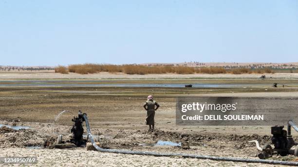 Man stands near water pumps drawing water from the Lake Assad reservoir, in the village of al-Tuwayhinah near the Tabqa Dam along the Euphrates river...