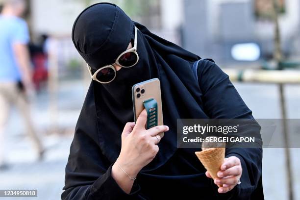 Middle Eastern woman takes a photo of ice cream in Lviv, some 540 km west of Kiev on August 13, 2021. Saudi tourists in traditional dress ride...