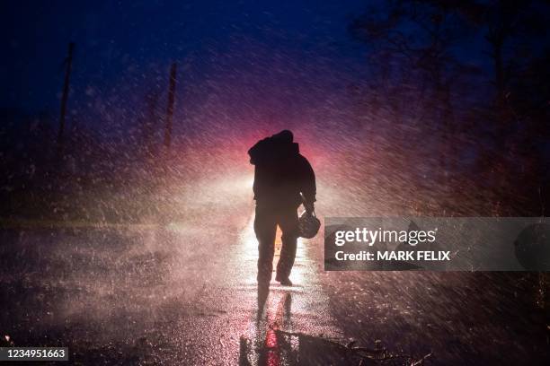 Montegut fire chief Toby Henry walks back to his fire truck in the rain as firefighters cut through trees on the road in Bourg, Louisiana as...