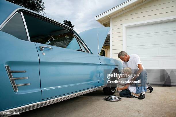 father and son changing a tire - old garage at home stock pictures, royalty-free photos & images