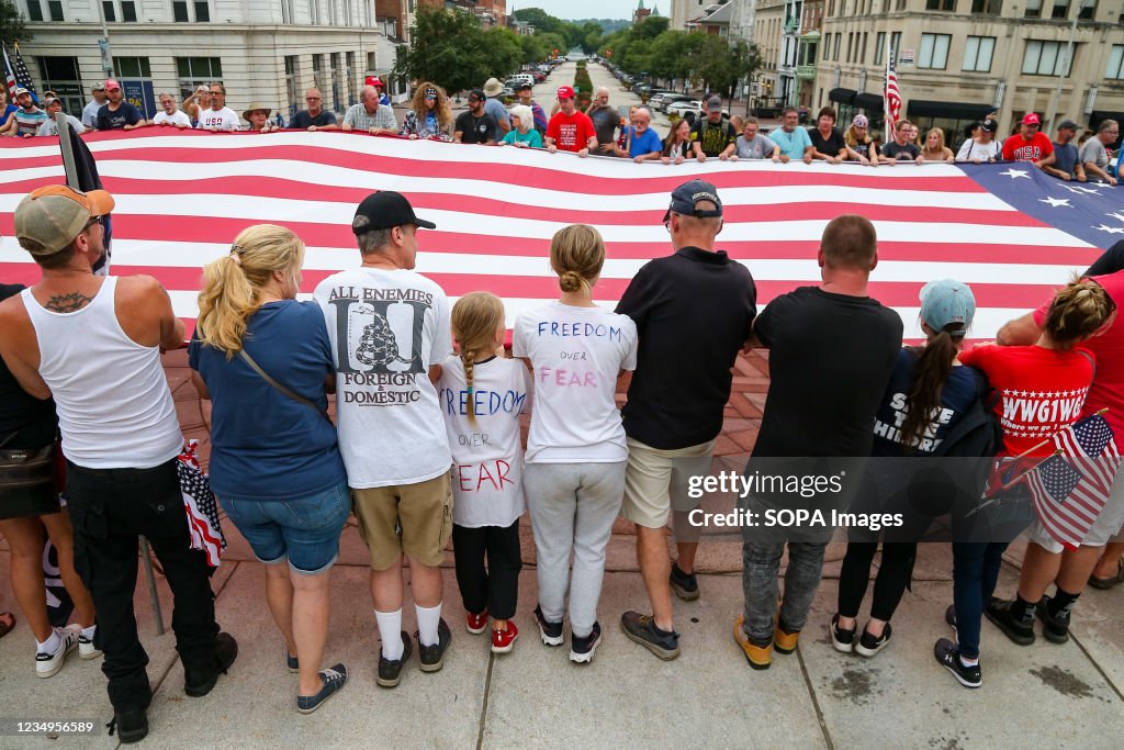 Protesters hold a huge American flag during the anti-vaccine...