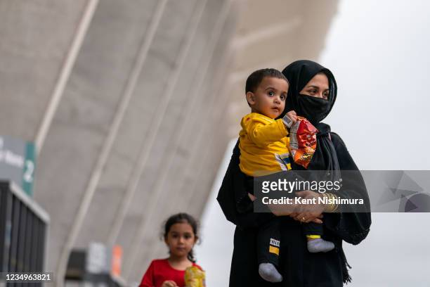 Evacuees who fled Afghanistan walk through the terminal to board buses that will take them to a processing center, Dulles International Airport on...