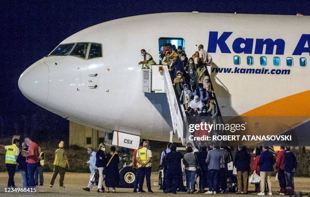 Afghan refugees step off a plane upon arrival at Skopje International Airport, in Skopje on August 30 after being evacuated from Kabul following the...