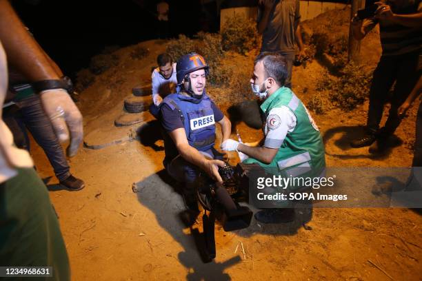 Journalists who were injured by tear gas canister fired by the Israeli soldiers towards the Palestinian protesters are seen along the border fence...