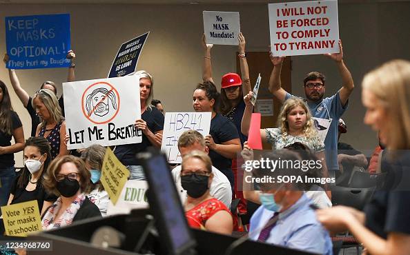 People demonstrate with placards at an emergency meeting of People demonstrate with placards at an emergency meeting of