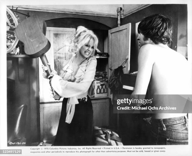 Goldie Hawn swings a guitar at Nicky Henson in a scene from the film 'There's A Girl In My Soup', 1970.