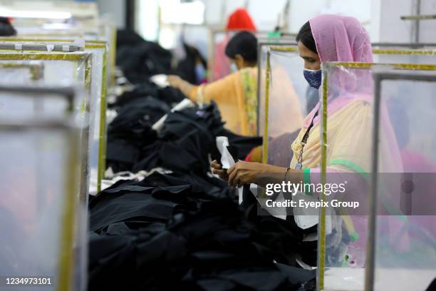 Woman worker wears face mask as preventive measure while manufactures clothes in a garment factory during the resume activities of industries amid...