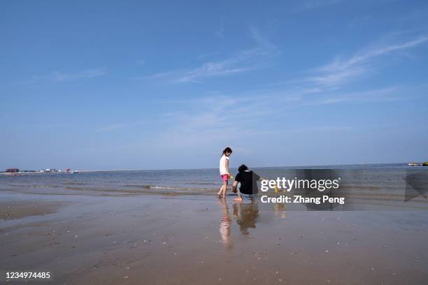 Little girl with her mother enjoys her summer vacations together on the beach. Just before the school is open, the Chinese government has issued a...